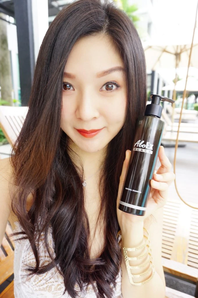 ผู้รีวิวถือผลิตภัณฑ์ AloEx แสดงผลลัพธ์ผมสุขภาพดีหลังใช้