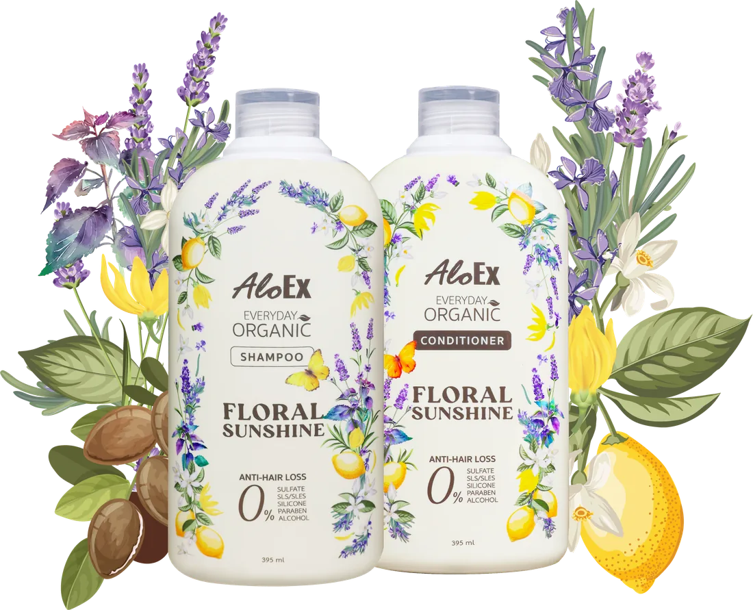 ขวดแชมพูและครีมนวด AloEx Everyday Organic Floral Sunshine วางคู่กัน ล้อมด้วยดอกลาเวนเดอร์ กระดังงา มะนาว และเมล็ดอาร์แกน